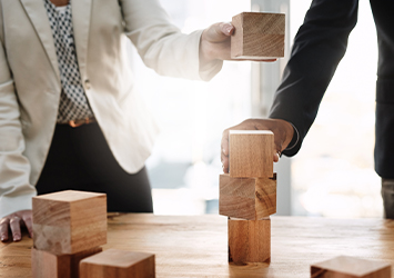 Gros plan sur des personnes en costume empilant des blocs de bois sur une table
