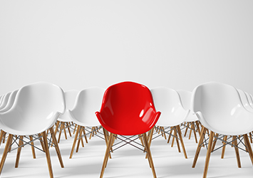 Rows of white chairs with one red chair front and centre